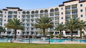 A multi-story hotel with a swimming pool and palm trees.