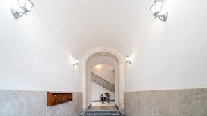 Una escalera de mármol con barandilla de metal, un letrero de madera y luces fijadas a la pared.