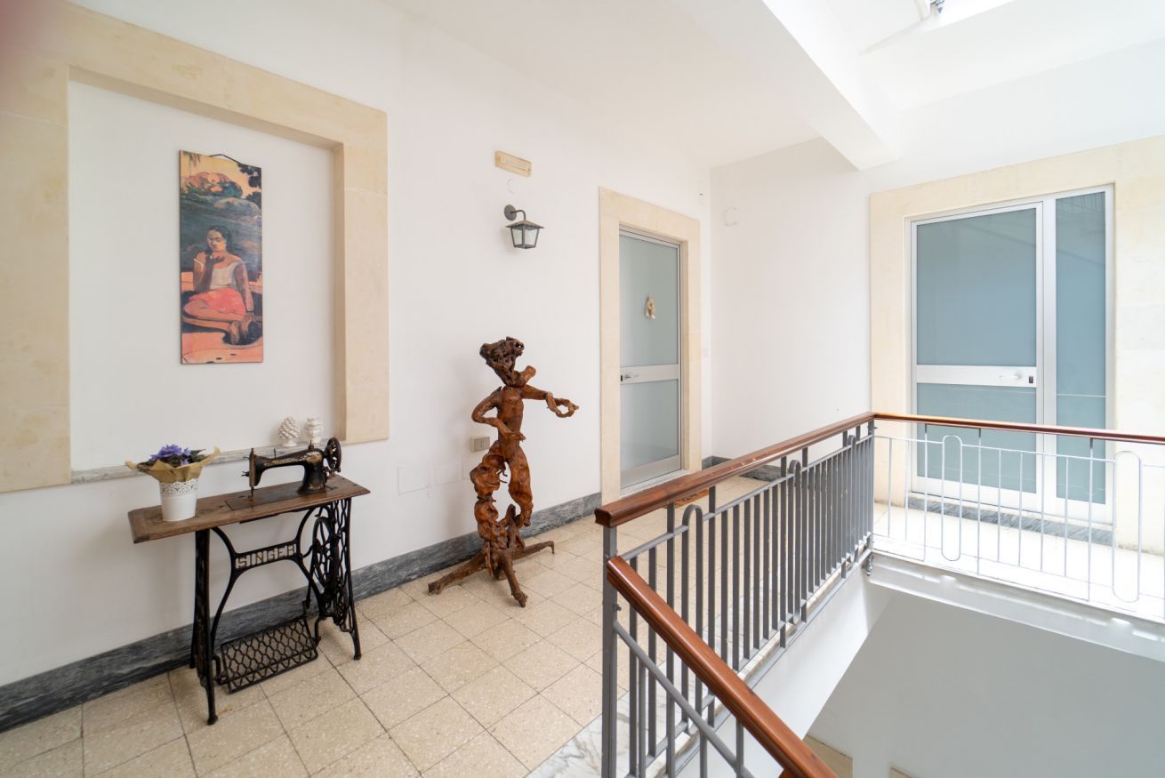 A room with a sewing machine, a sculpture, a framed painting, and a door with a frosted glass window.