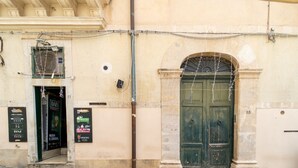 Un edificio con puerta verde, un letrero y un ventanal pequeño.
