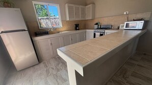 Eine Küche mit Kühlschrank, Herd, Mikrowelle und Schränken.