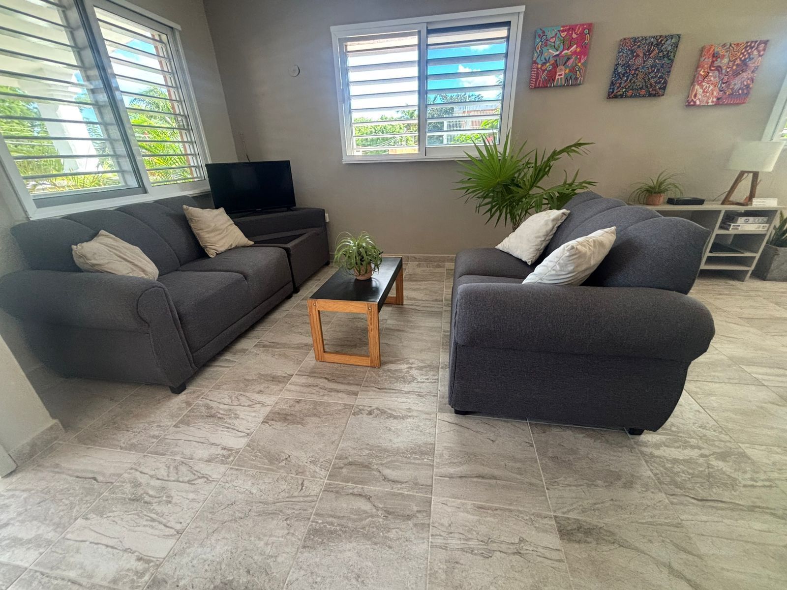A living room with two sofas, a coffee table, a TV, and a window with blinds.