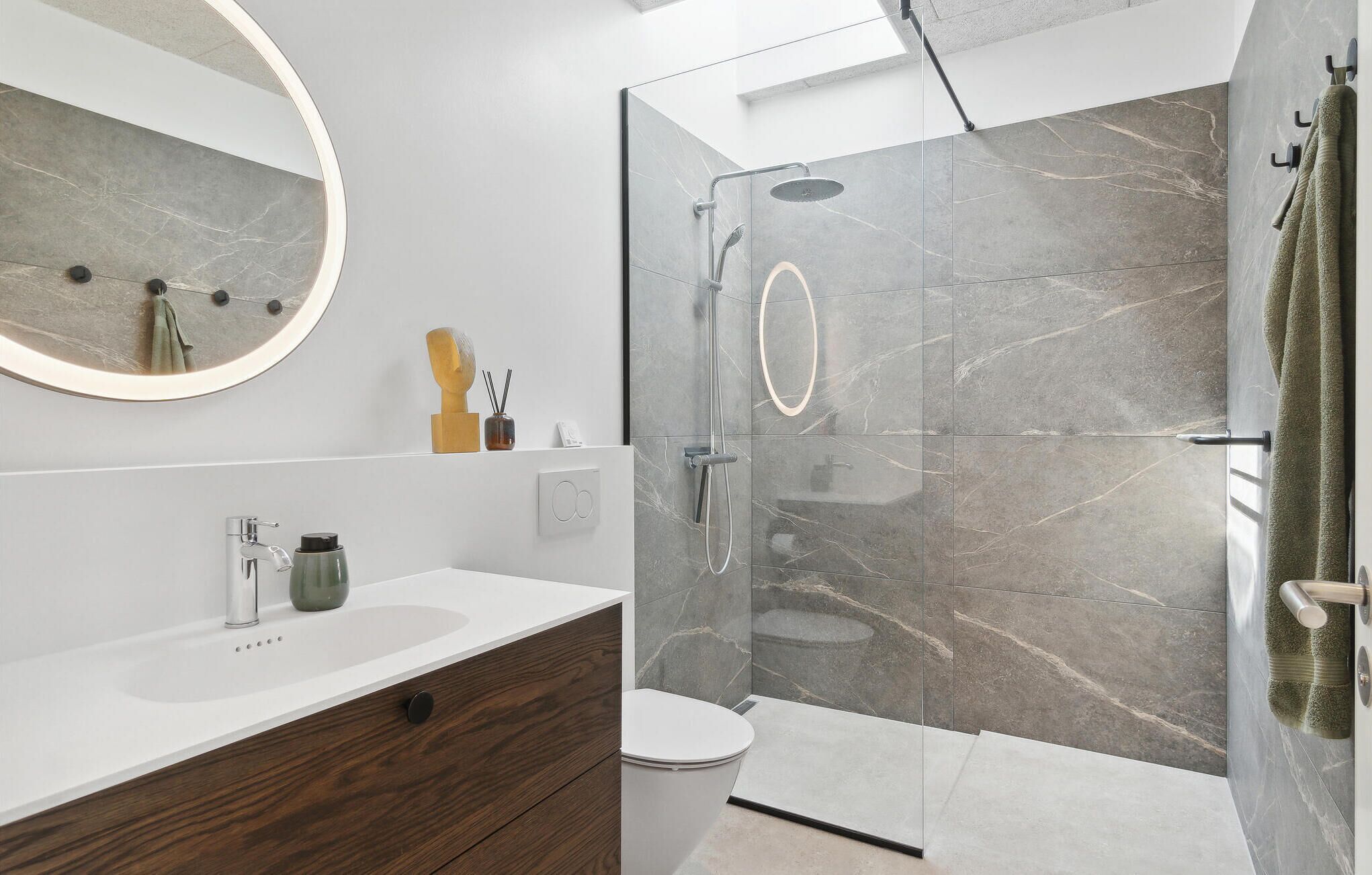 A modern bathroom with a glass shower enclosure, a white sink, and a wooden vanity.