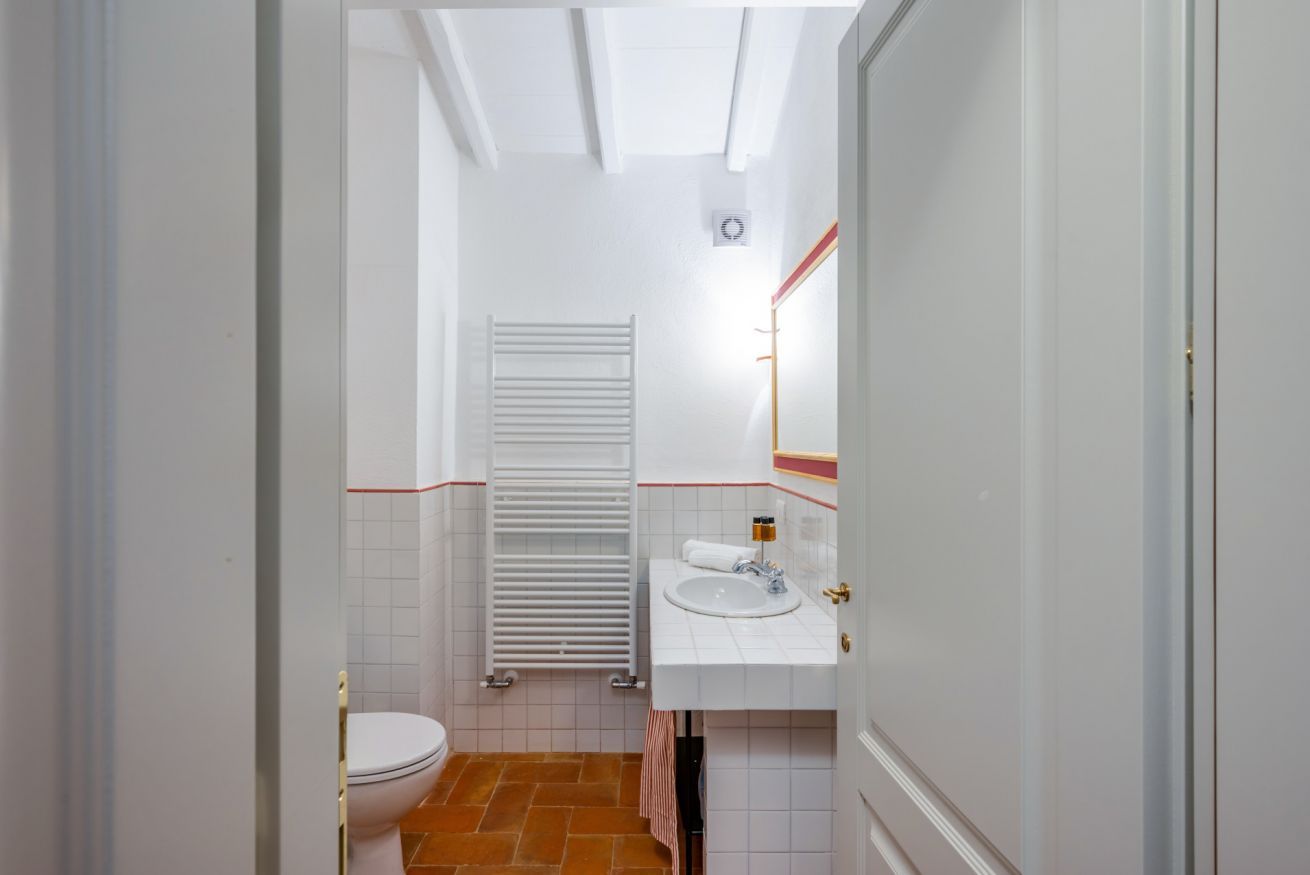 Un baño con inodoro, lavamanos y toallero.
