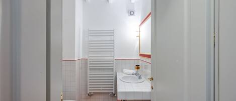 Un baño con inodoro, lavamanos y toallero.