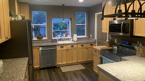 Una cocina moderna con armarios de madera, electrodomésticos de acero inoxidable y vistas al exterior a través de amplias ventanas.