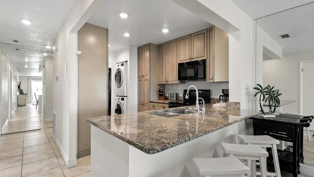 A modern kitchen with granite countertops, stainless steel appliances, and a central island with bar stools.