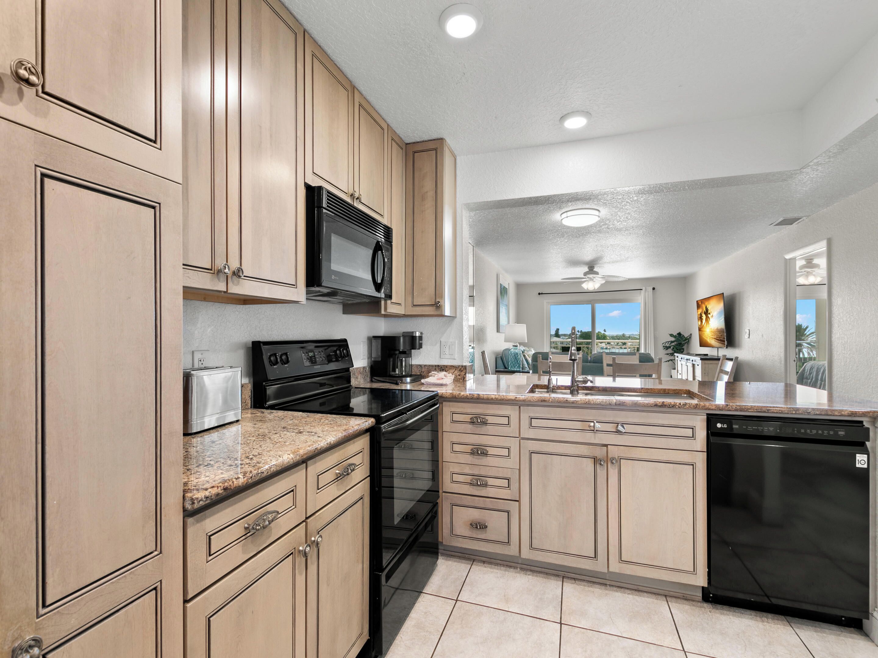 A modern kitchen with wooden cabinets, a black microwave, stainless steel appliances, and a dishwasher.