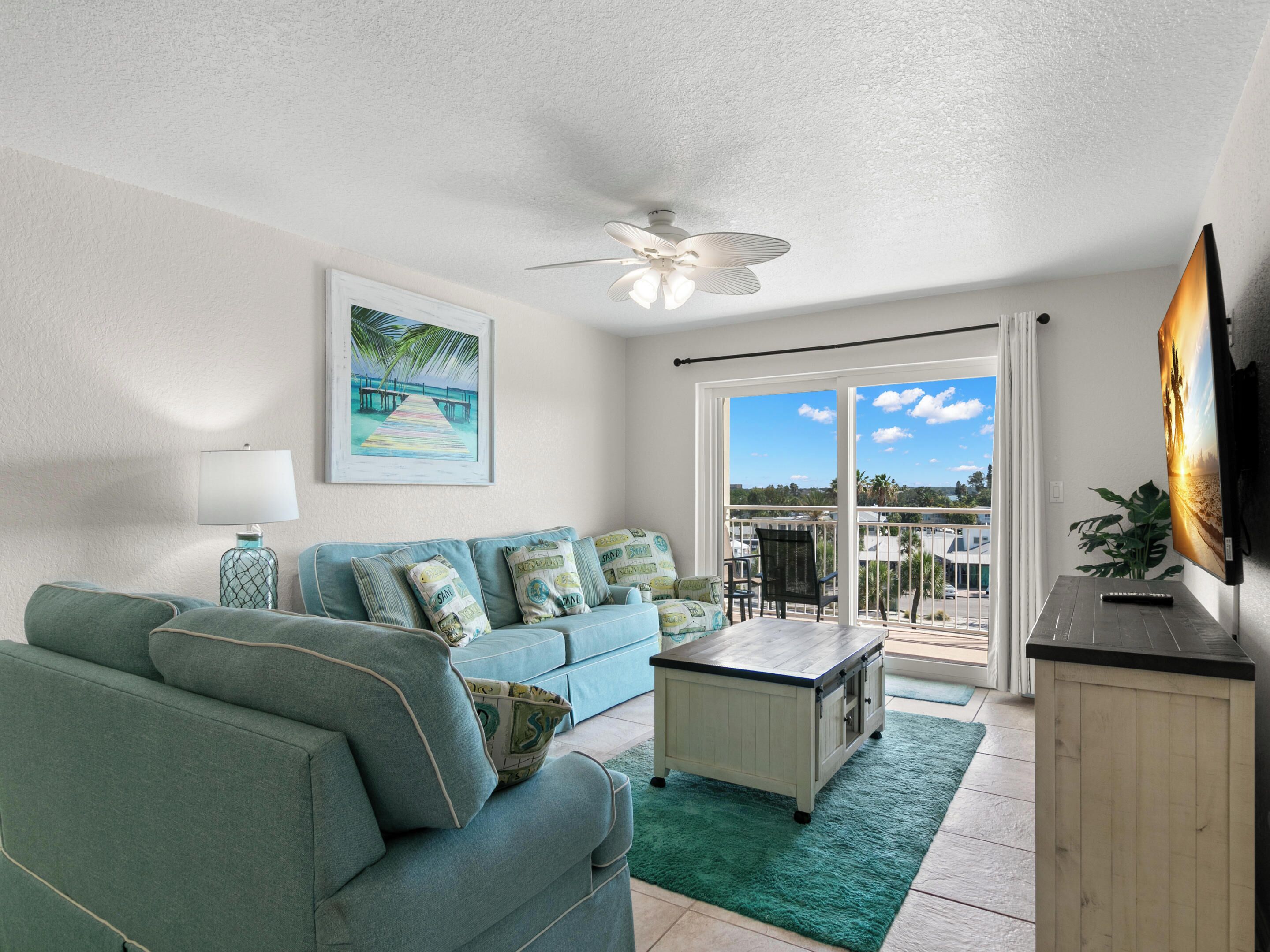 A living room with a sofa, a coffee table, a TV, and a balcony with a view.