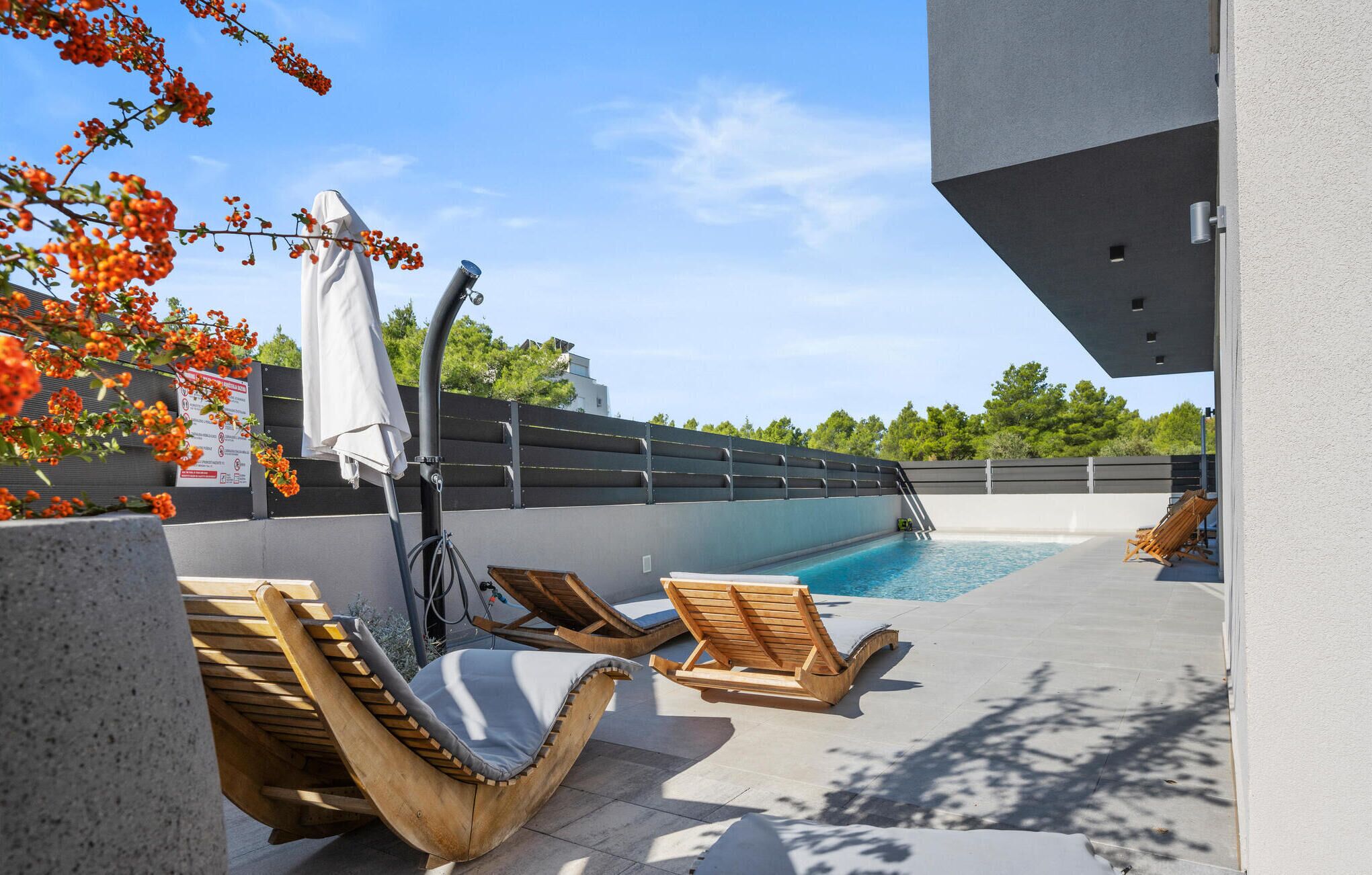 A rooftop pool area with wooden loungers and a covered seating area.