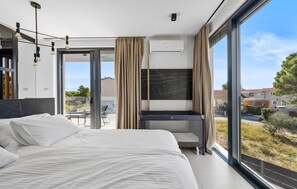 Relax in a spacious room with a large bed, desk, and flat-screen TV, offering a view of the surrounding landscape.