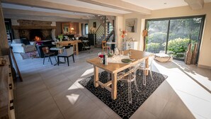 Un amplio salón con chimenea, una mesa de comedor y una escalera que sube a un nivel superior.