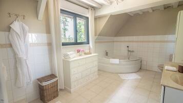 A modern bathroom with a freestanding bathtub, a vanity with a mirror, and a window with curtains.