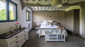 Un dormitorio con cama, mesitas de noche, cómoda, ventana y puerta.