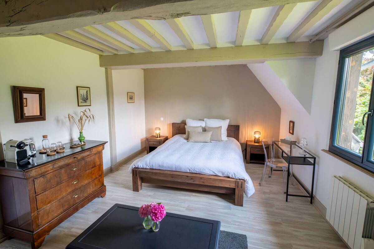Un dormitorio con cama de madera, mesitas de noche, cómoda y ventana.