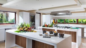 Une cuisine moderne dotée d’un îlot central, d’appareils électroménagers intégrés et offrant une vue sur un paysage verdoyant.