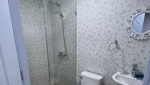 Ein Badezimmer mit Duschkabine, Toilette, Waschbecken und Spiegel.
