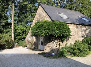 Un bâtiment en pierre avec un toit en pente, une petite fenêtre et une porte.