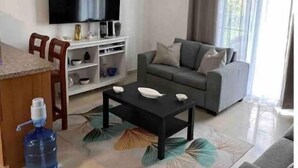 A living room with a sofa, a coffee table, a TV, and a ceiling fan.