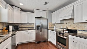 A kitchen with white cabinets, stainless steel appliances, and a tiled backsplash.