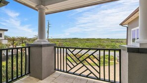 A balcony with a view of a green landscape and a clear sky.