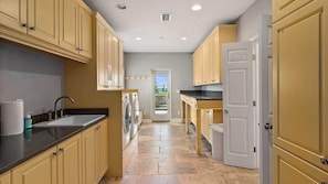 A kitchen with beige cabinets, a black countertop, a sink, and a door leading to a balcony.
