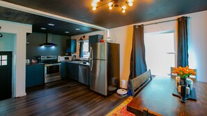 A modern kitchen with dark wood flooring, stainless steel appliances, and a unique ceiling light fixture. - An Alluring Escape (Cincinnati)
