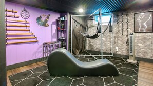 A gym with exercise equipment, a yoga mat, and a wall with a geometric design. - An Alluring Escape (Cincinnati)