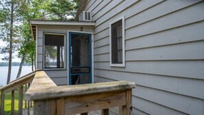 A wooden deck leading to a house with a number '2' sign, a window, and a view of a lake.