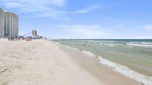 A beach with a large hotel on the left, featuring multiple floors and a crane. - Admirals Quarters 802 - Coastal Luxury with Endless Gulf View (Orange Beach)