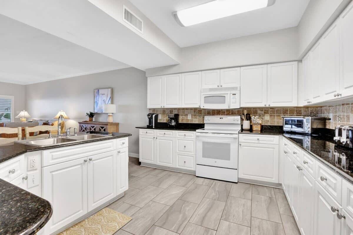 A modern kitchen with white cabinetry, a black countertop, and a microwave.