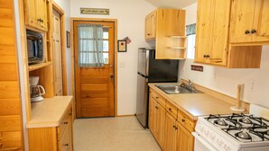 Una cucina compatta con mobili in legno, un frigorifero, un fornello e un lavello.