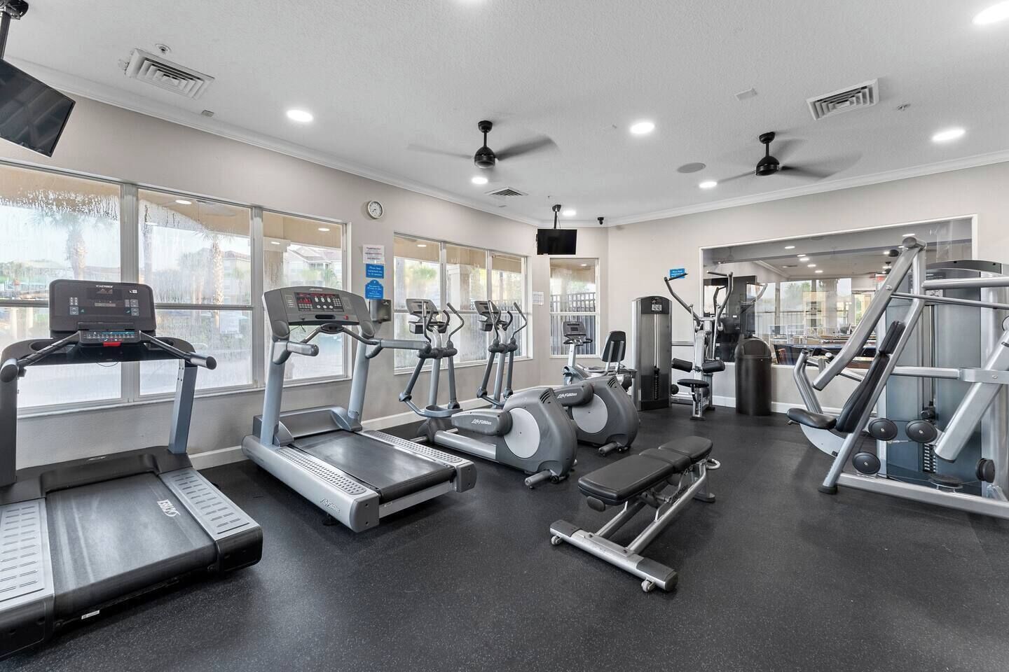 Une salle de sport équipée de tapis de course, de vélos elliptiques et de matériel de musculation.
