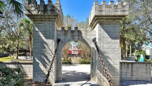 Un arco in pietra con catene, che conduce a un edificio con dettagli rossi.