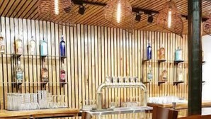Een bar met houten lambrisering, hangende lampen en een toog met krukken.