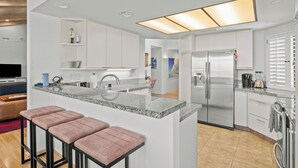 A modern kitchen with a central island, stainless steel appliances, and a bright overhead light.