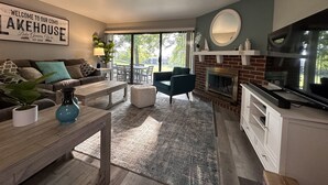 Una sala de estar moderna con chimenea, televisor y comedor con vistas al exterior.