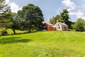 A rural landscape with a stone house and a wooden barn.