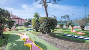 Un jardin bien entretenu, avec un sentier sinueux, des haies soigneusement taillées et une variété d’arbres.