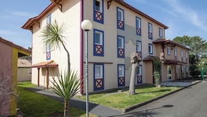 Un immeuble à plusieurs étages, doté d’une façade symétrique, de nombreuses fenêtres et d’une entrée centrale.