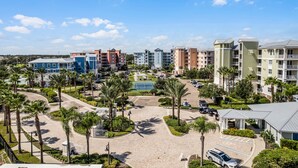 A multi-story hotel complex with a central courtyard, palm trees, and a tennis court. - Riverwalk Condos - Calm Waters! Overlook the intercoastal! (New Smyrna Beach)