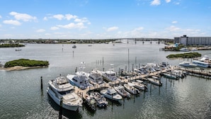 A marina with boats docked, a bridge in the background, and a small island with greenery. - Riverwalk Condos - Calm Waters! Overlook the intercoastal! (New Smyrna Beach)