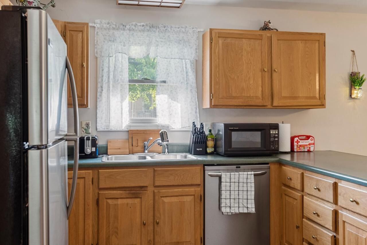Une cuisine avec des meubles de rangement en bois, un réfrigérateur en acier inoxydable, un four à micro-ondes, un grille-pain et un évier.