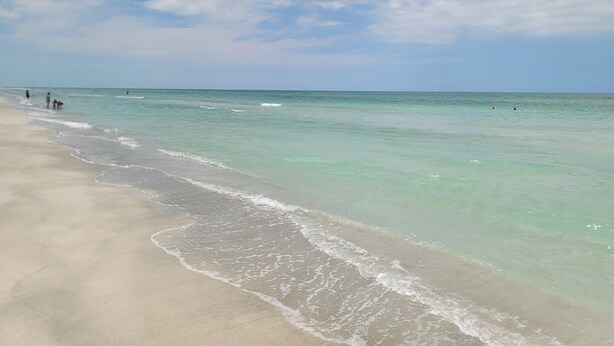 A beach with clear turquoise water and a sandy shore.
