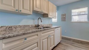 A kitchen with light blue walls, a granite countertop, and white cabinetry.