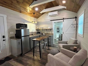 A compact kitchen with modern appliances, a dining area with stools, and a cozy seating area with a sofa and a small table.