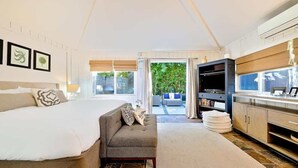 A bedroom with a bed, a sofa, a TV, and a view of the outdoors. - Secluded Windansea Beach Rental Cottage (La Jolla)