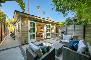 A small house with a patio, outdoor seating, and a garage. - Secluded Windansea Beach Rental Cottage (La Jolla)