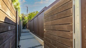 A narrow pathway flanked by wooden fences, leading to a gate. - Secluded Windansea Beach Rental Cottage (La Jolla)