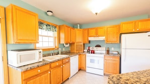 A kitchen with wooden cabinets, a microwave, a sink, a stove, and a refrigerator.
